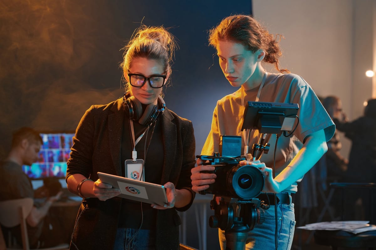 Waist up portrait of two women working in video production crew and looking at digital tablet screen copy space