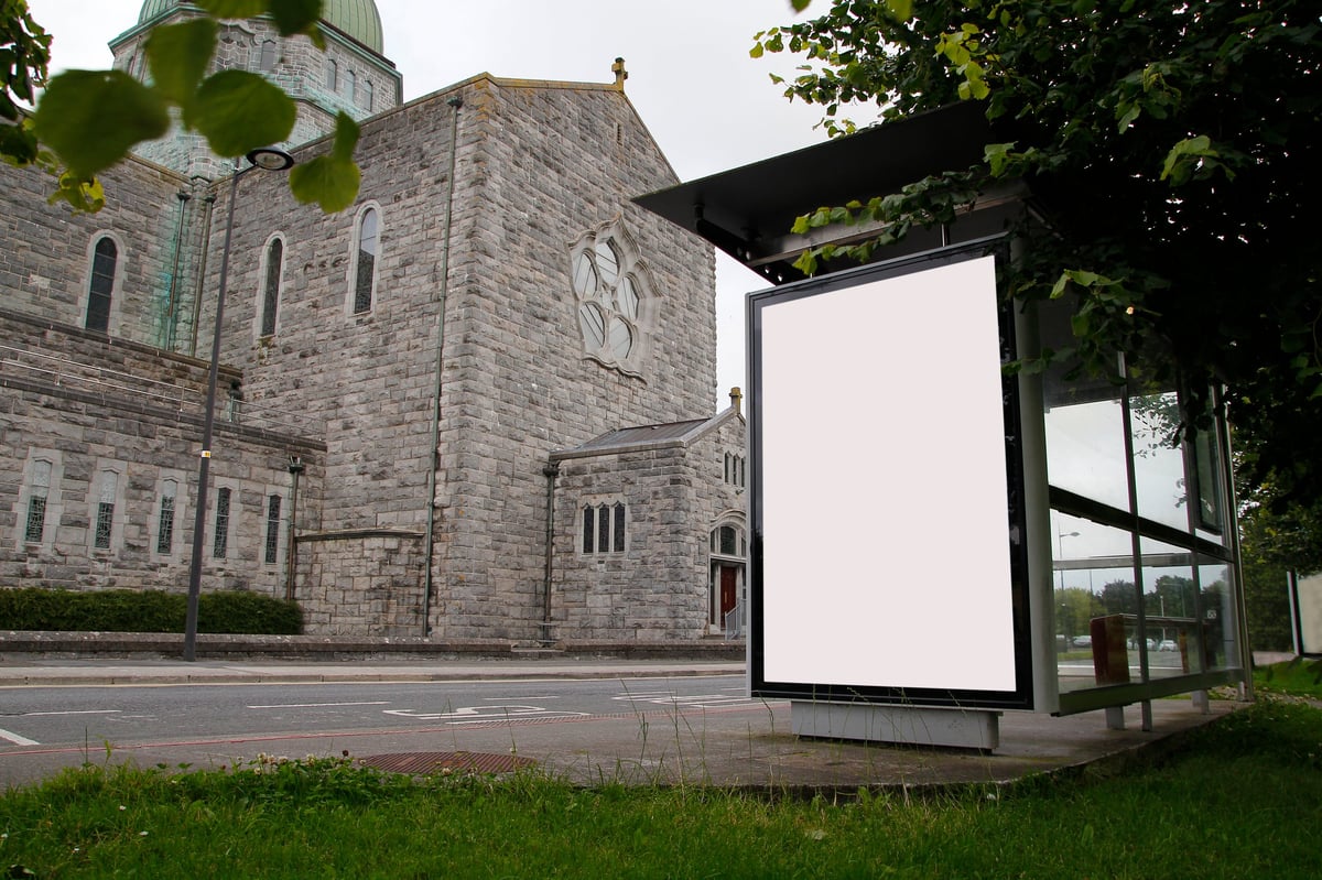 Blank billboard in a bus stop, with a church in the background